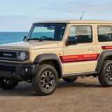 Beige Suzuki Jimny with red stripes in a front three-quarter coastal view