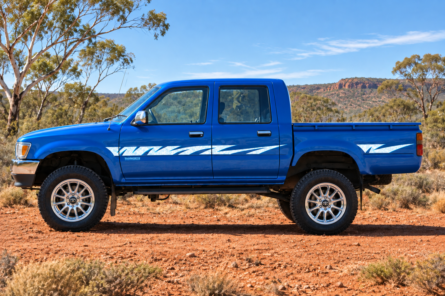 Blue Toyota Hilux in outback setting with chrome mag wheels