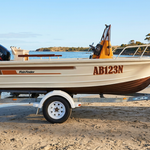 The Quintrex boat with its Fish Finder stripes and AB123N lettering on a sandy beach with calm coastal water behind