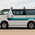 White HiAce with navy and teal stripes beside the coast
