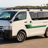 White HiAce with solid green stripes at a coastal lookout, front three-quarter view